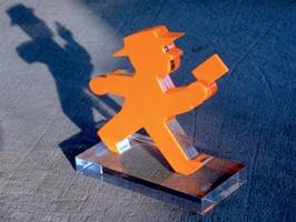 Foto zeigt einen Award mit einer gehenden Postmann-Figur mit Brief in einer Hand.Die Figur ist aus Sandwich-verklebten Acrylglas (orange auf farblos) und steht auf einer Grundplatte aus farblosem Acrylglas.