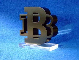 Foto zeigt einen Award aus lackiertem Acrylglas. Zwei Bs sind ineinander geschachtelt. Das große B in der Mitte steht auf einer Grundplatte aus farblosem Acrylglas.