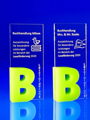 Acrylglas Awards auf farblosem Acrylglas mit Lasergravur für Buchhandlungen. Unten links auf den Awards sind beidseitig aus dickerem, grünen Acrylglas aufgeklebte Bs, die dem Award genug Standfläche geben um nicht umzufallen.